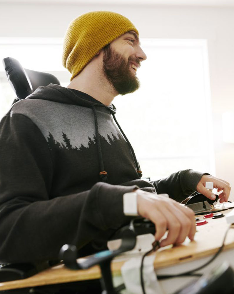 A smiling male gamer using an adaptive controller in a bright room.