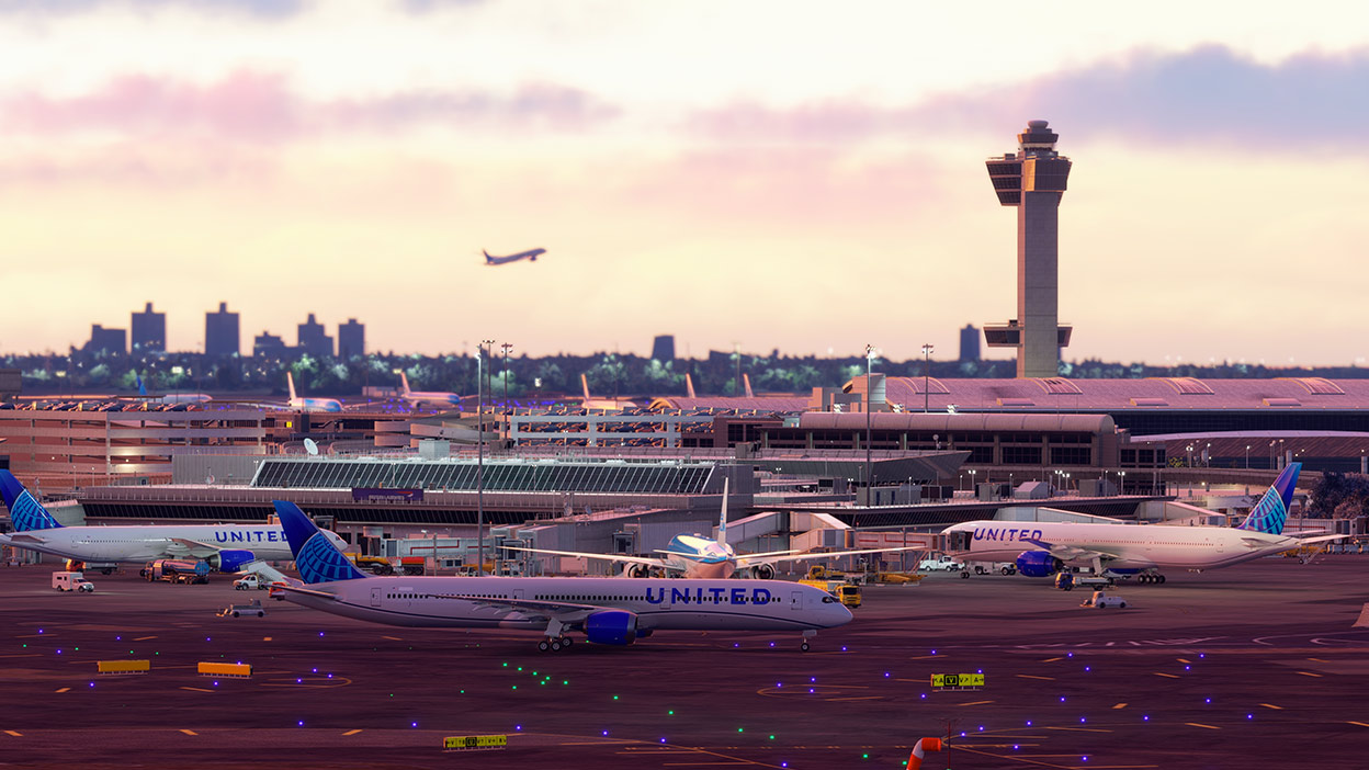 An airport at dusk with commercial airplanes sitting at their terminals. 