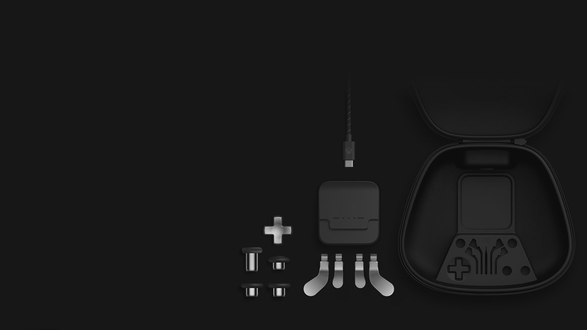 Izometrický pohled na obsah úplné sady komponent: palcové ovladače, směrový ovladač, páčky, nabíjecí stojan, kabel USB-C a pouzdro pro přenášení.